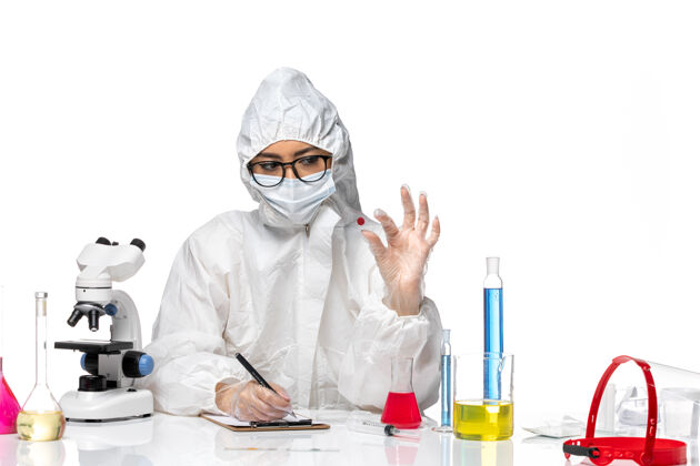 西装前视图身着特殊防护服的女化学家在白色背景上检查样本病毒化学成分可预防大流行健康实验室外套检查健康