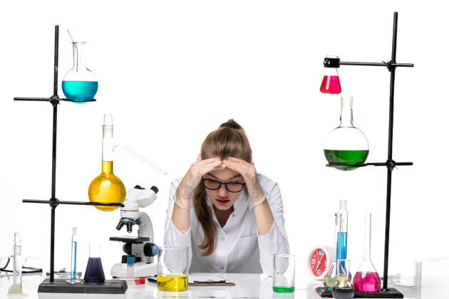 实验室前视图：身着医疗服的女化学家坐在桌子前面 白色背景上有溶液化学大流行性冠状病毒焦点医学病毒