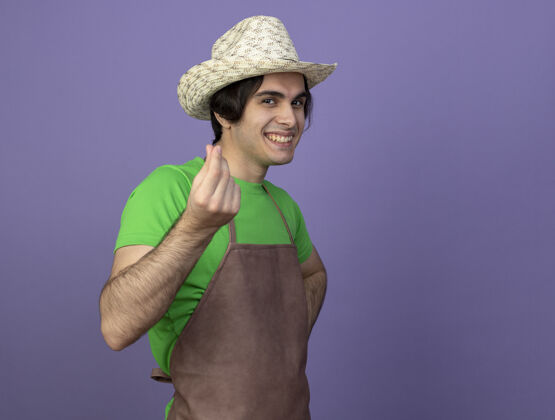 表演微笑的年轻男园丁穿着制服 戴着园艺帽 展示着小费的姿势帽子手势制服