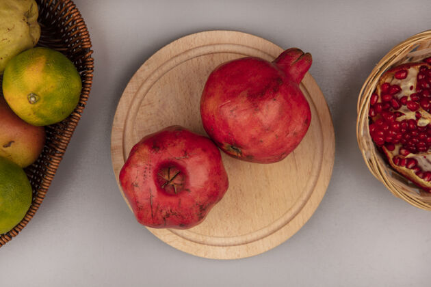 石榴新鲜石榴在木制厨房板上的顶视图 桶上放着橘子食品厨房健康
