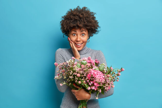 蓝色喜气洋洋的非裔美国妇女在生日接受祝贺收到鲜花时有着惊喜的表情开花姿势请
