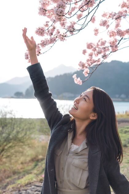 花亚洲女人欣赏她周围的大自然开花樱花日本