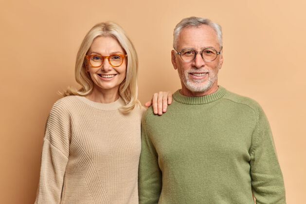 女人半身镜头的中年妇女和男子微笑愉快地穿套头衫和眼镜关系金发眼镜
