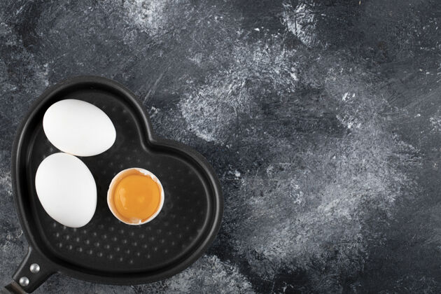 鸡蛋两个白鸡蛋和蛋黄放在心形锅上新鲜有机菜肴