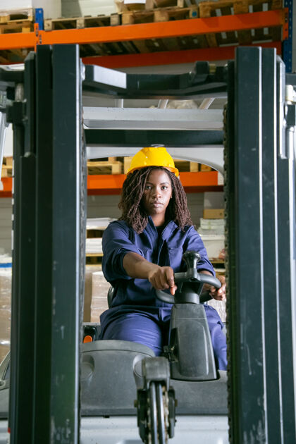 工作严肃的女仓库工人戴着安全帽开着叉车 看着前面技术信心操作