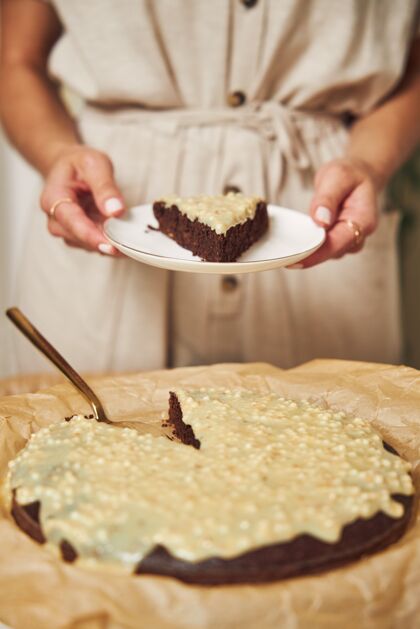 桌子年轻的女厨师在白色的桌子上做着美味的奶油巧克力蛋糕烘焙布丁糖果