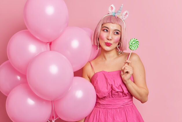 棒棒糖粉红色头发的快乐梦幻女人 手里拿着绿色的圆糖果 棒棒糖似的饮食美味美味