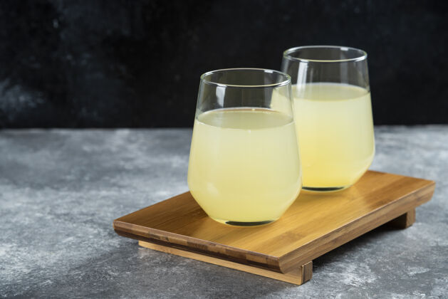 罐装的两杯柠檬水放在木桌上切片的新鲜的液体