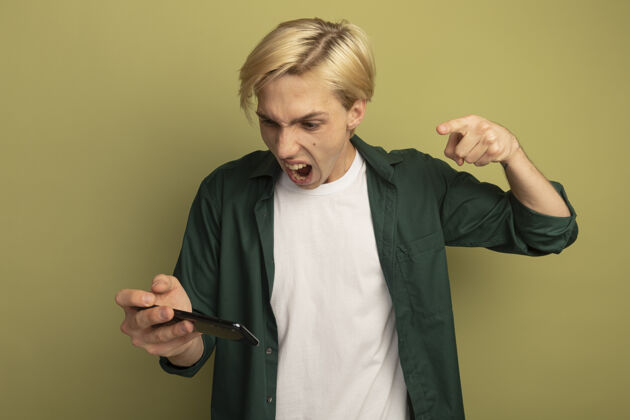 点愤怒的年轻金发男子穿着绿色t恤拿着电话指着男人金发人