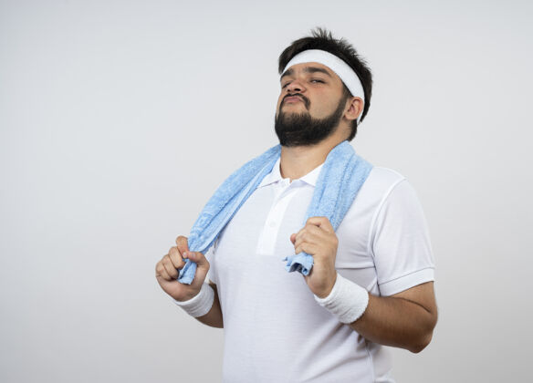 腕带自信的年轻人戴着头带和腕带 肩上带着毛巾 隔离在白色墙壁上 留有复制空间运动头带肩膀