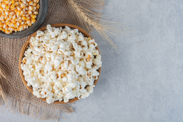 谷物一碗爆米花 一罐玉米和一根麦秆放在大理石表面的一块布上配料面粉脆