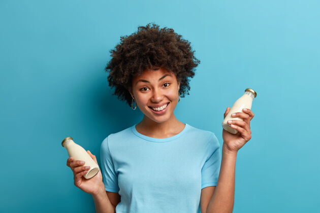 满意纯素食物和营养概念快乐的深色皮肤卷发女人拿着一瓶新鲜杏仁牛奶食物奶制品姿势