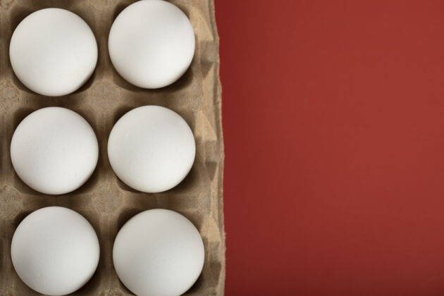 食物红色表面上的白色鸡蛋容器纸箱鸡蛋食物