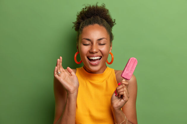 美国喜出望外的千禧一代女人梳着卷发笑得很开心 吃着美味的草莓冰淇淋食物积极欣喜若狂