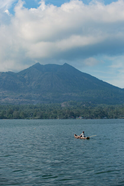 孤独一个人在船上游泳 俯瞰着火山天空水冒险