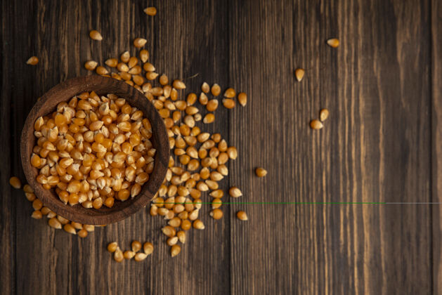 新鲜木碗上的有机新鲜玉米粒俯视图 木桌上的玉米粒与复印空间隔离谷物果仁食物