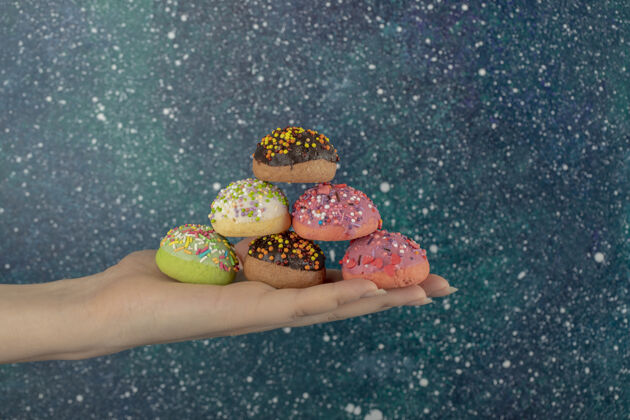 霜冻女人手里拿着五颜六色的甜甜圈和花洒不健康的饮食面包房甜甜圈