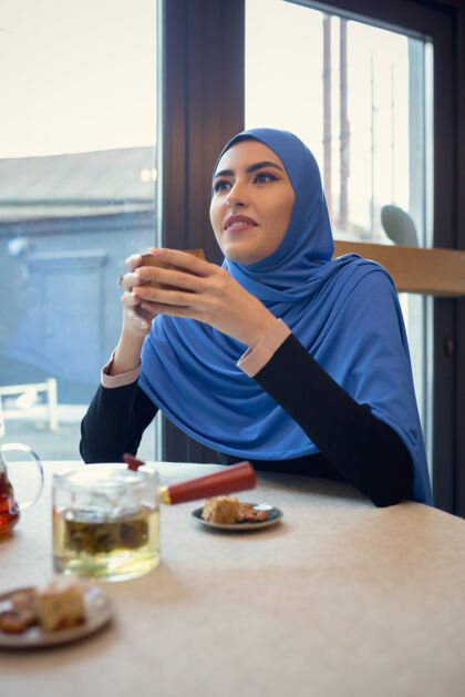 屏幕使用设备美丽的阿拉伯女人在咖啡馆或餐厅聚会 朋友或商务会议一起度过时光 交谈 欢笑生活方式时尚快乐的化妆模特面部办公室化妆品