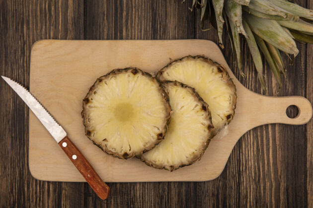 木材木制厨房板上的甜菠萝俯视图 木制背景上有刀菠萝顶部膳食
