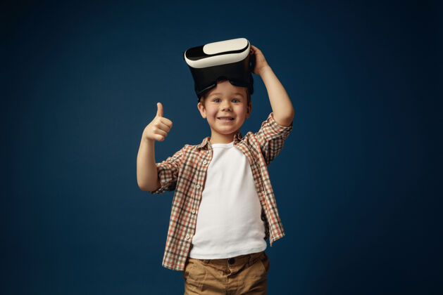 游戏好的标志小男孩或孩子穿着牛仔裤和衬衫 戴着虚拟现实耳机眼镜 蓝色工作室背景尖端技术 电子游戏 创新的概念女性视觉科技