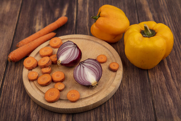 观点新鲜蔬菜的俯视图 如切碎的胡萝卜和红洋葱放在木制厨房板上 胡萝卜和黄色甜椒被隔离在木制背景上洋葱胡萝卜红色