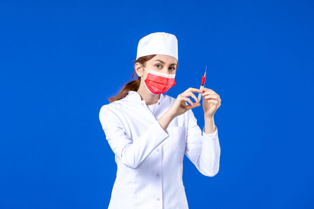 疾病正面图：身穿白色医疗服的女护士 戴着红色面罩 手上拿着蓝色针剂医院手面罩