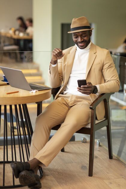 手机在咖啡馆工作的现代非洲裔美国人男士男士现代