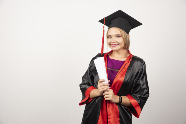 年轻美丽的女学生穿着长袍拿着毕业证书高质量的照片女孩Cap微笑