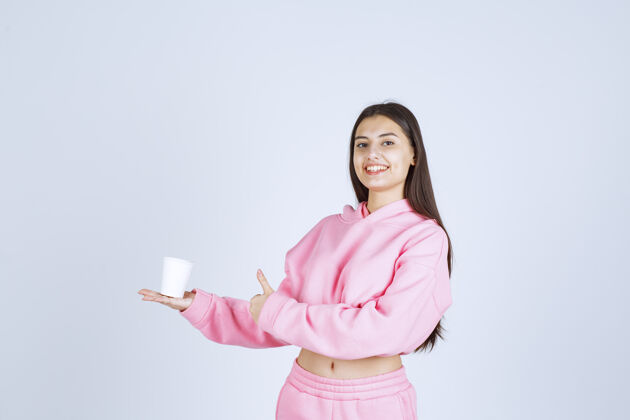 冬天穿着粉色睡衣的女孩捧着咖啡杯 享受着咖啡的味道人积极喜欢