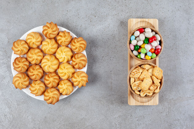 盘子一盘自制饼干 两碗饼干和糖果放在大理石背景的托盘上高品质照片糖果零食饼干