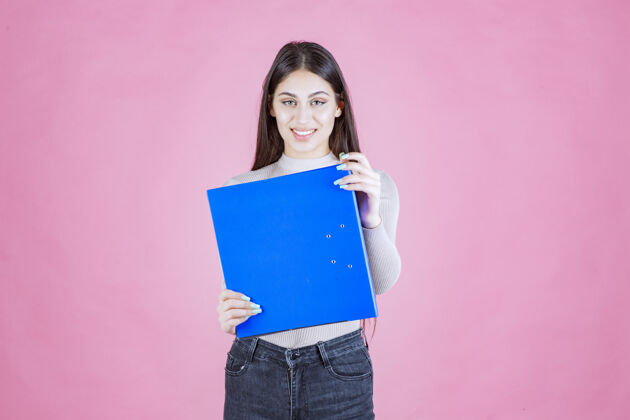 休闲女孩拿着一个蓝色的项目文件夹 看起来很成功和快乐人清单成人