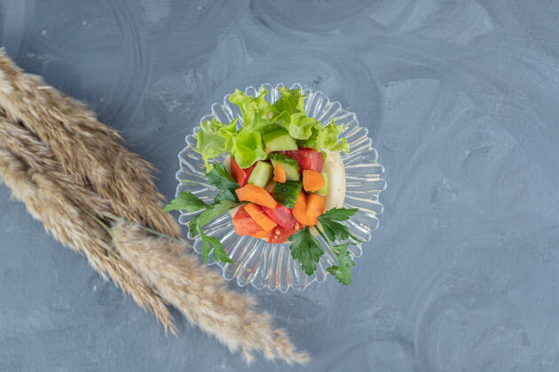 美味一小块羊肉沙拉放在大理石背景上一大块干针叶草旁边沙拉生菜胡萝卜