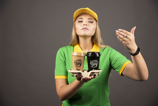 帽子女送货员闻咖啡杯在黑暗的背景高品质的照片女士人女