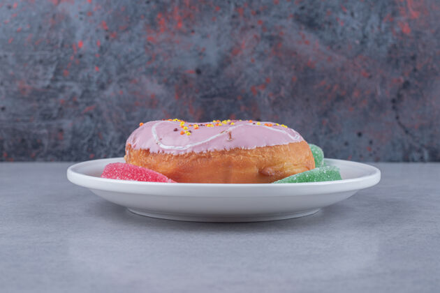 甜点在大理石表面的盘子上放一个烤面包和一个甜甜圈美味糕点美味