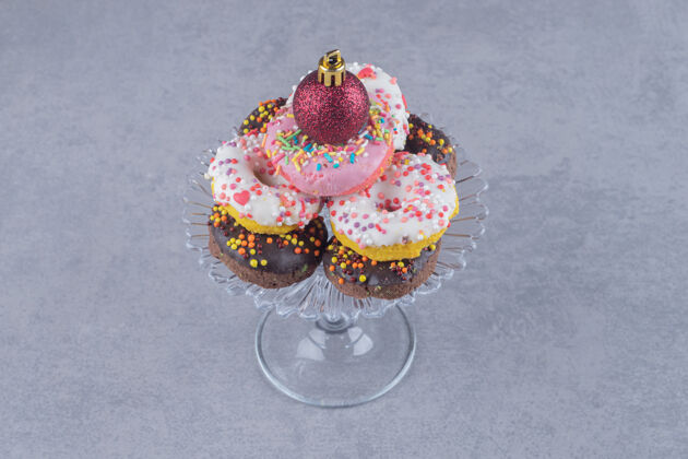 糖果大理石表面有一堆甜甜圈的玻璃底座美味顶部甜点
