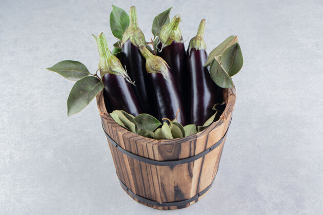 桶叶子和茄子在桶里 在大理石表面营养健康美味