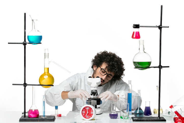 实验室前视图穿着白色特别套装的年轻男科学家正在修理显微镜瓶子科学化学