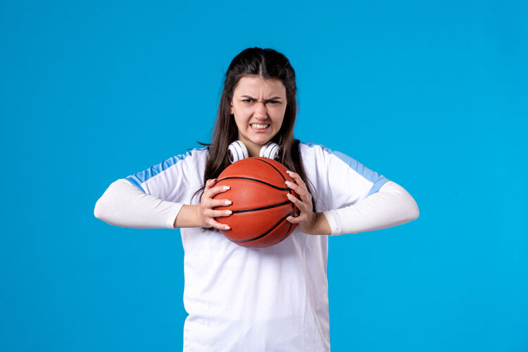 青年正面图：蓝色墙上挂着篮球的年轻女子蓝色女人人物