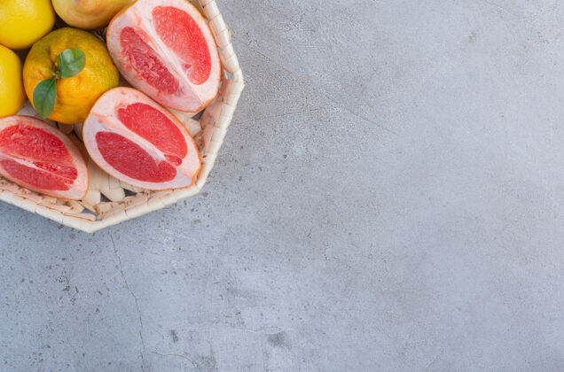 美味雪梨和葡萄柚片放在大理石背景上的白色篮子里美味柚子风味