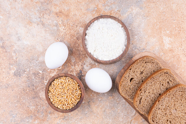 小麦鸡蛋 谷物 面粉和面包放在一个木头盘子里 放在大理石上营养鸡蛋谷类