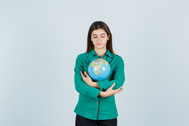 黑发年轻的女士穿着衬衫拥抱着地球仪 小心地看着前方健康护理地球仪
