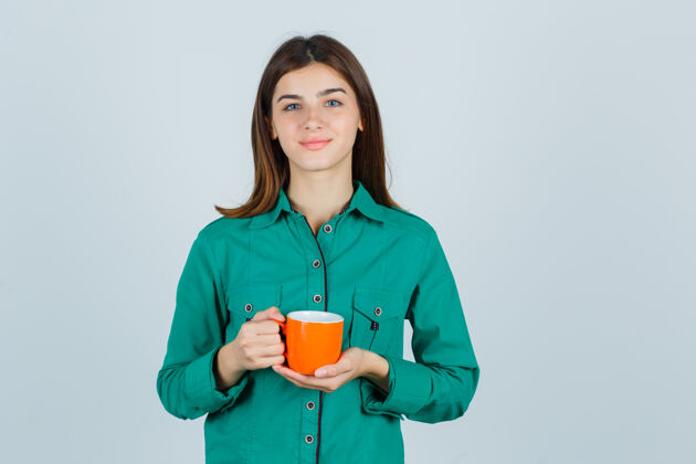 卷发年轻的女士拿着一杯橘色的茶 穿着衬衫 看上去很平静漂亮女士衬衫