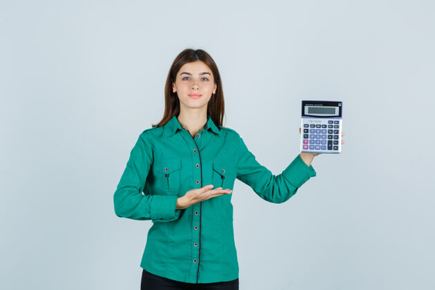 专业身着绿色衬衫的年轻女士展示计算器 看起来很自信 正面视图商务模特女士