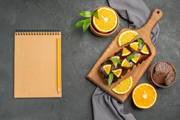 毛巾笔记本上放着柔软可口的蛋糕 橘子和饼干放在木制的砧板和毛巾上沙拉午餐美食