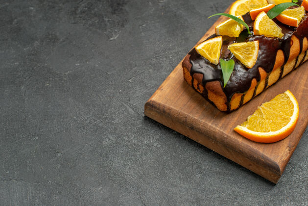 盒子美味的蛋糕装饰着橘子和巧克力在黑桌子的砧板上巧克力食物座位