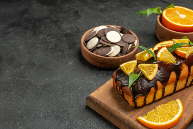 盘子在黑暗的桌子上的砧板上 美味的蛋糕切橘子和饼干的半张照片板一半水果