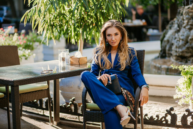 春天在阳光明媚的秋日里 一位身着优雅蓝色套装的微笑美女坐在咖啡馆里夹克女性性感
