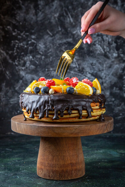 蛋糕正面是美味的巧克力蛋糕和新鲜水果在黑暗的墙上水果糖前面