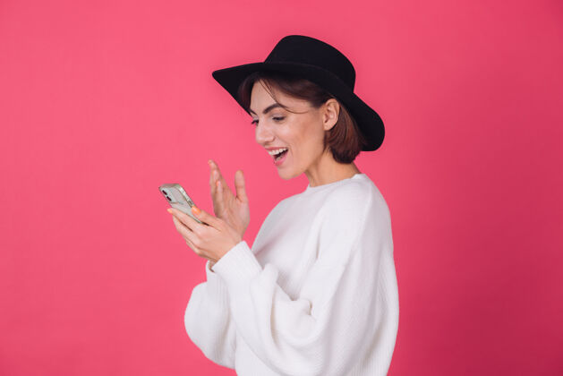 华丽穿着白色休闲毛衣 戴着红粉色帽子的时髦女人互联网电话应用程序