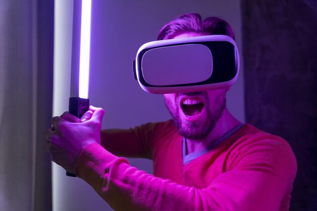 娱乐男人用虚拟现实耳机玩激光剑享受乐趣房子